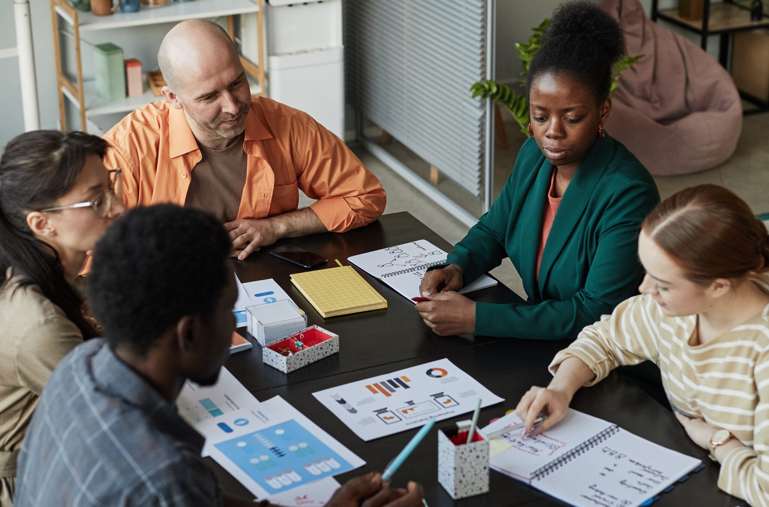 Vertical high angle view of creative business team at meeting table discussing project