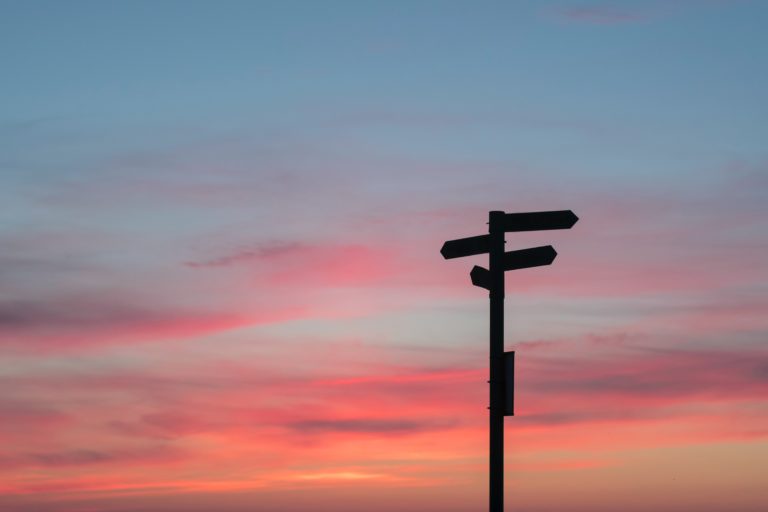 directional signs with a pink sky