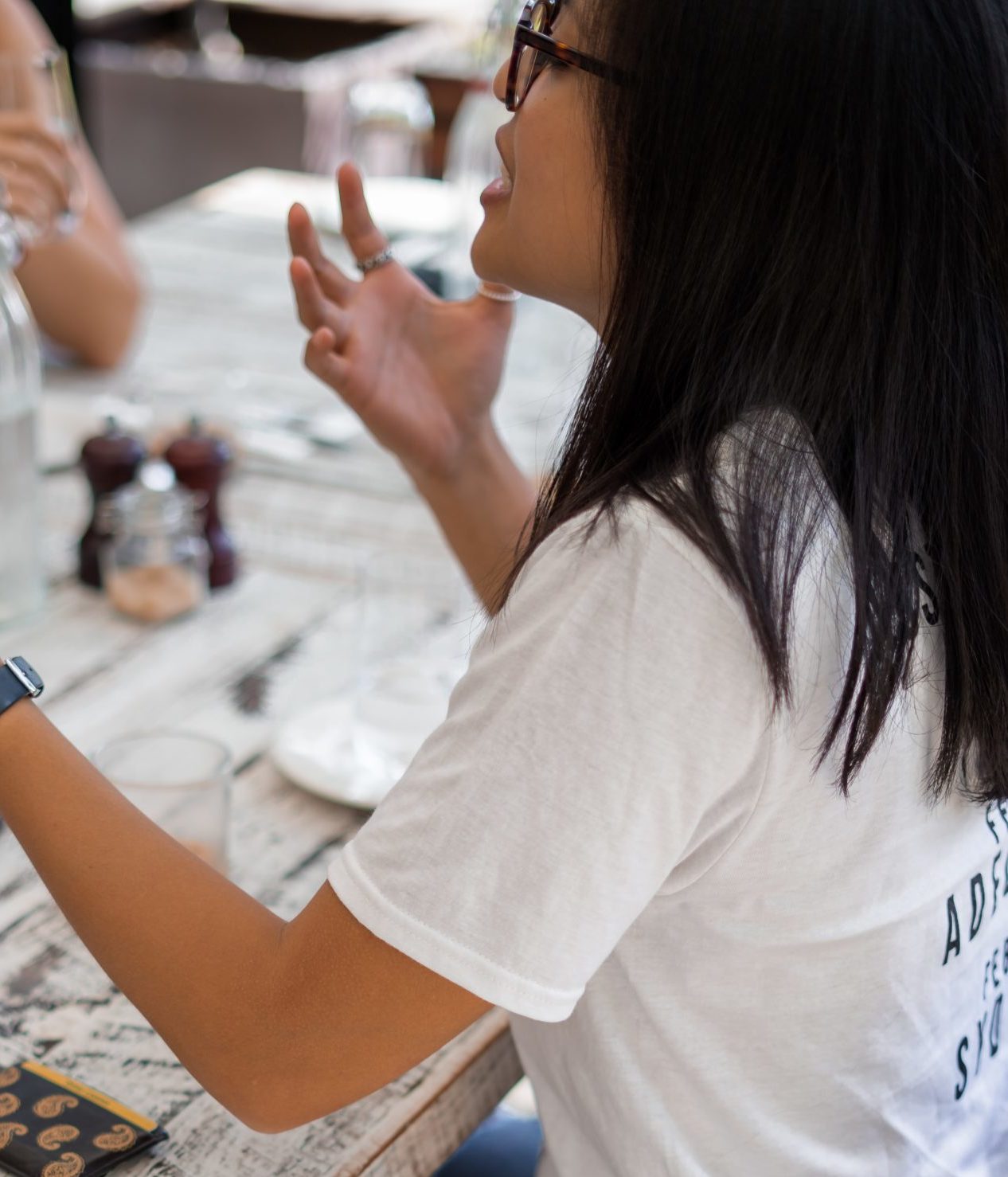 Young asian woman having a conversation at a table, using hand gestures