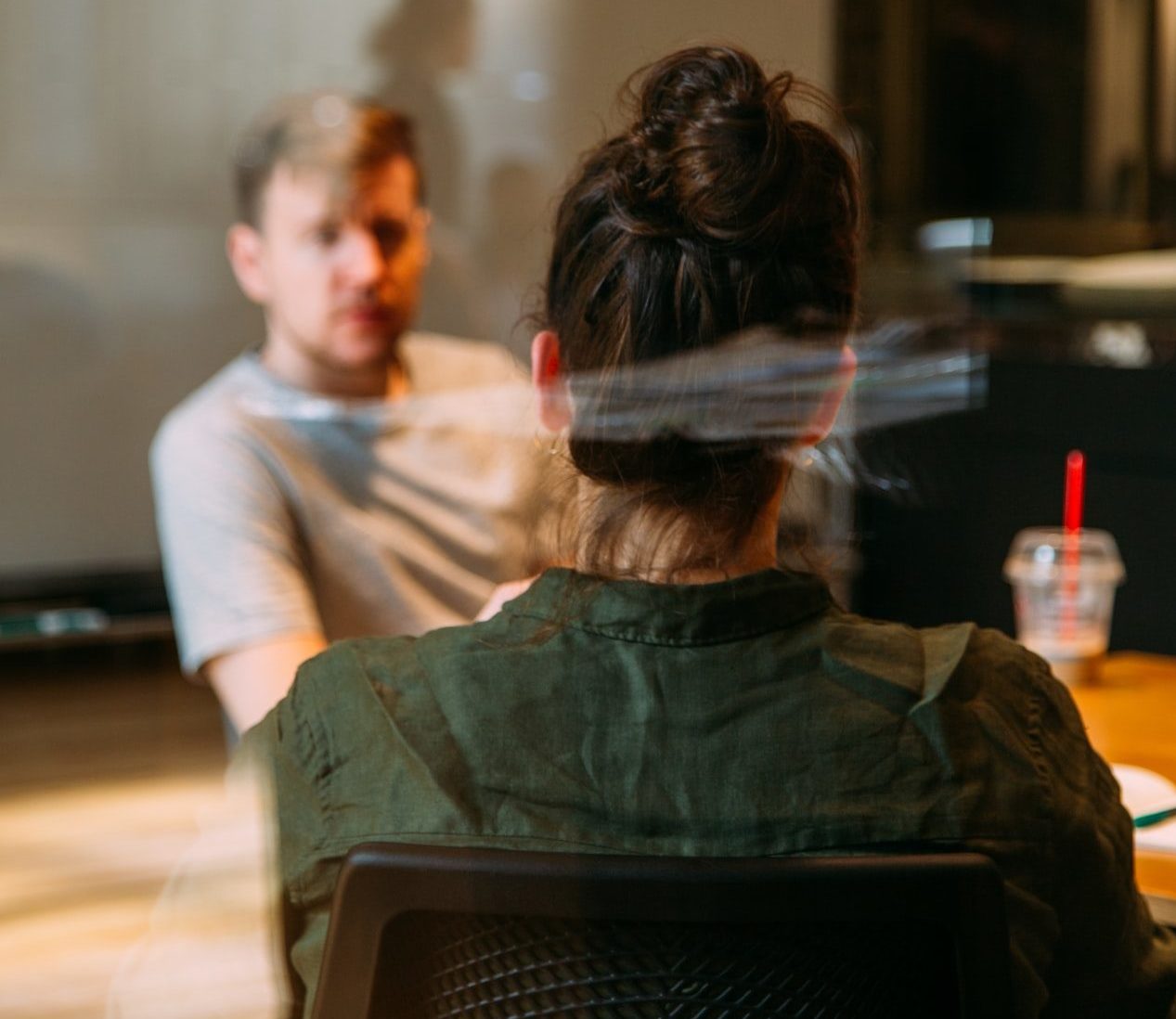 through a window pan you see a man facing a woman and they appear to be in a conversation