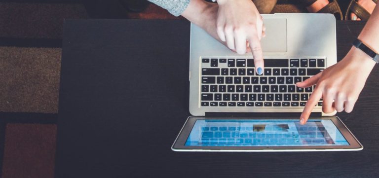 a group of young people point to a laptop screen