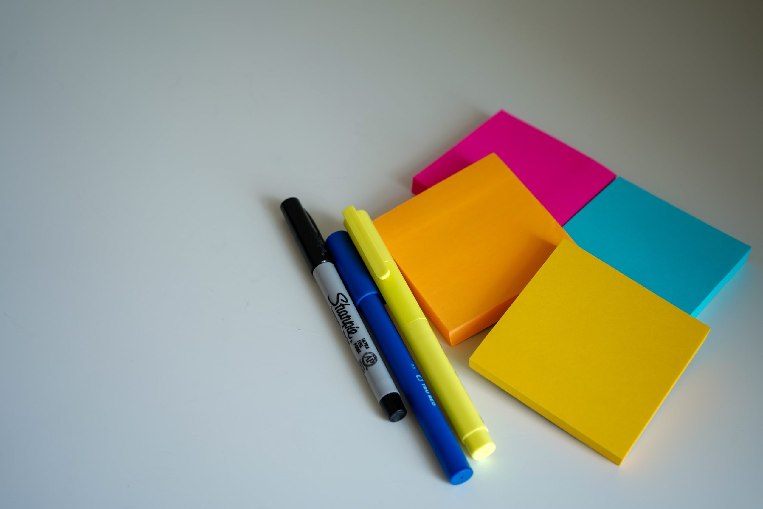 a pile of different coloured post-it notes and pens