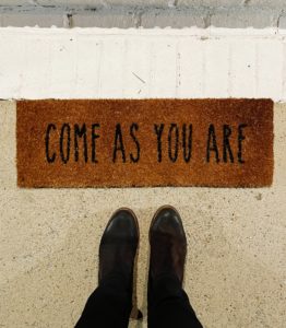 feet on a doormat that says come as you are