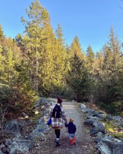 a woman walks down a path holding her son's hand