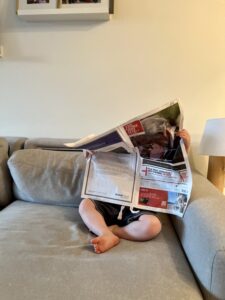 a toddler reads a newspaper