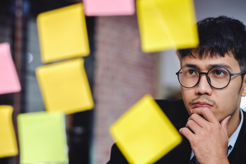 asian businessman looking and writing on sticky note for brainstorming