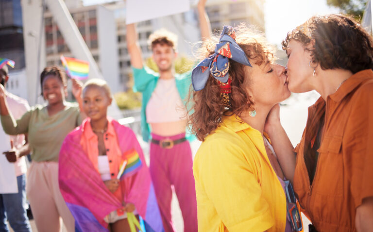 Two women kiss in front of friends.