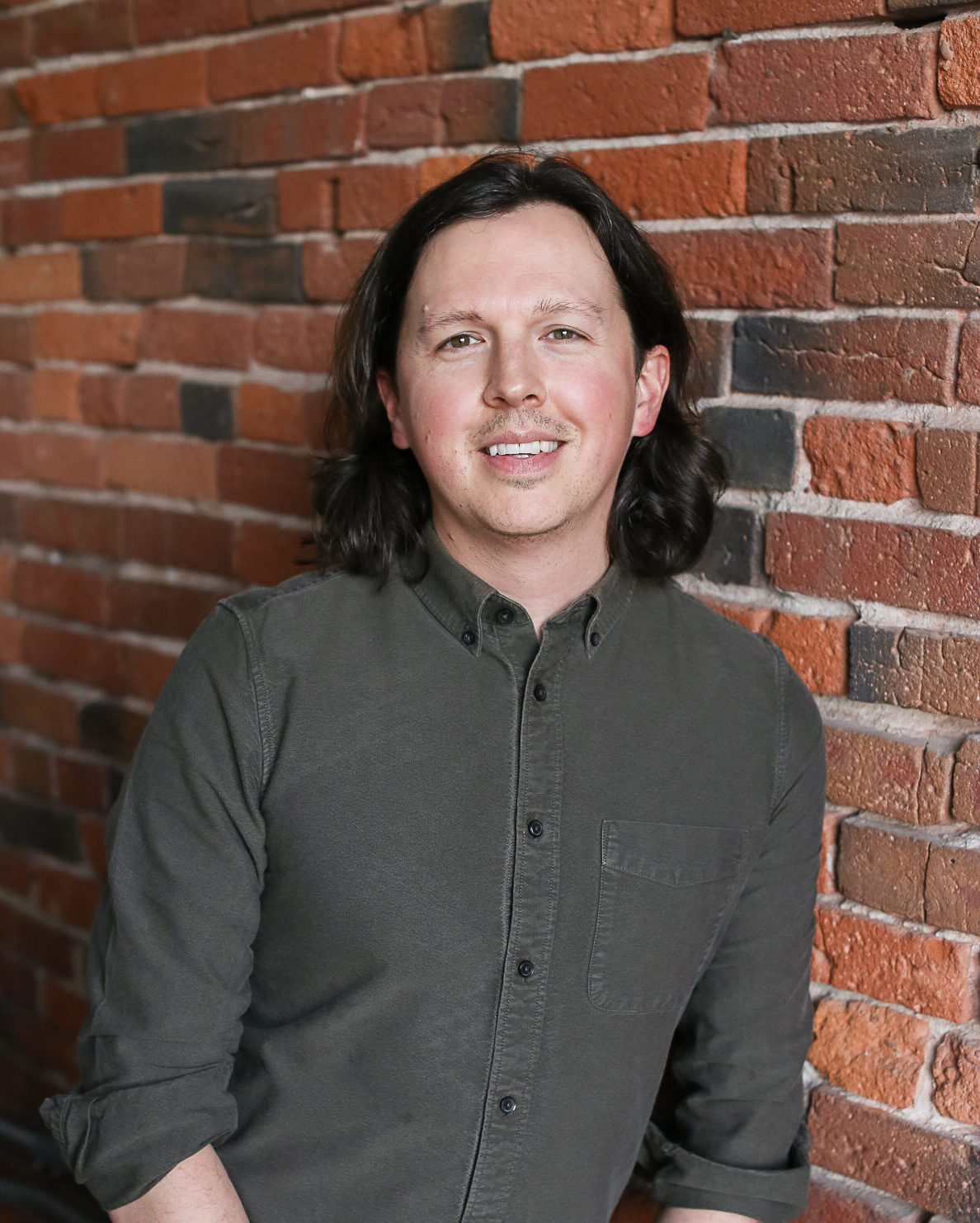 headshot of zach bulick man with shoulder length brown hair and green shirt