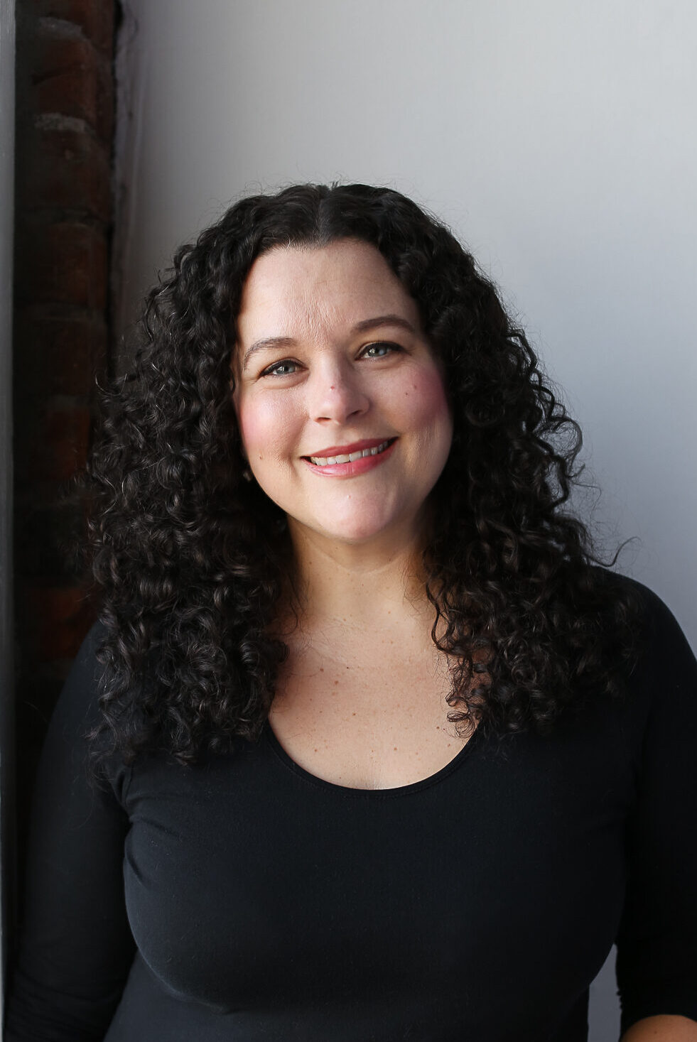 photo of alison gallagher with curly dark brown hair and black shirt