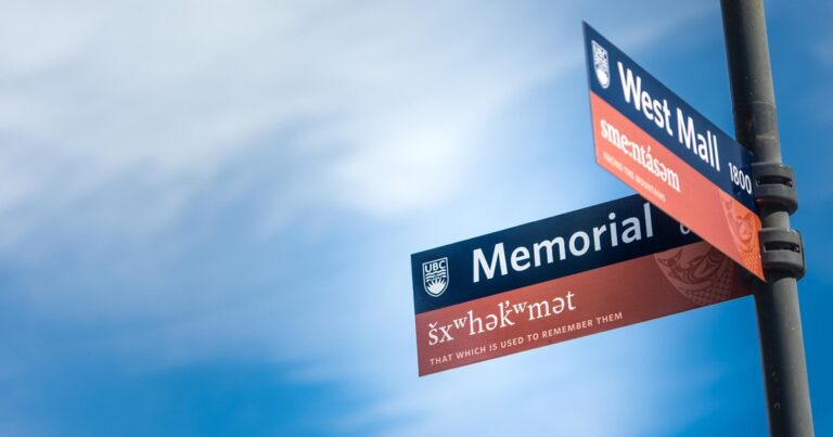 a blue sky with white whispy clouds and two bilinugla street signs on a pole from the UBC campus