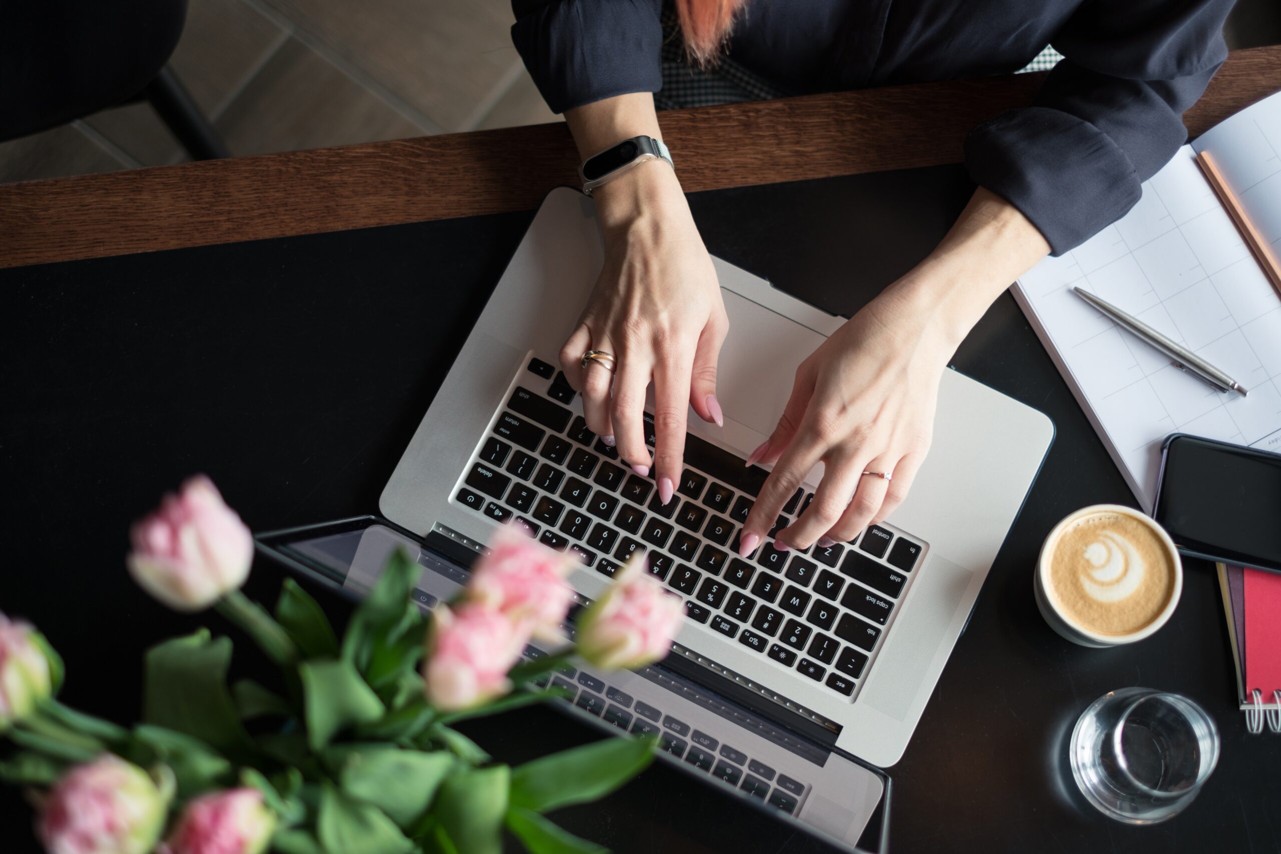 aerial view of woman typing on a laptop with flowers nearby